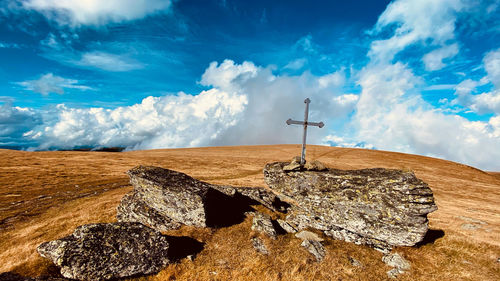 Cross on rock against sky