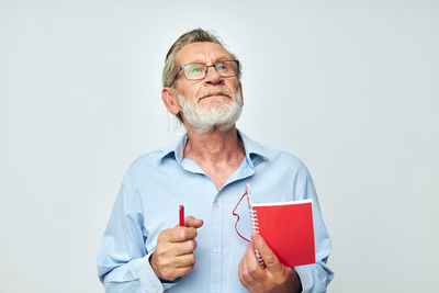 Senior man holding diary against white background