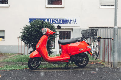 Red motor scooter parked on street in city
