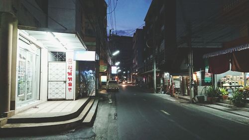 Empty road amidst buildings in city at night