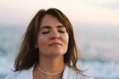 Portrait of a happy young girl with closed eyes on a background of beautiful sea.