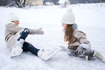 Cute sisters playing on snow covered land during winter