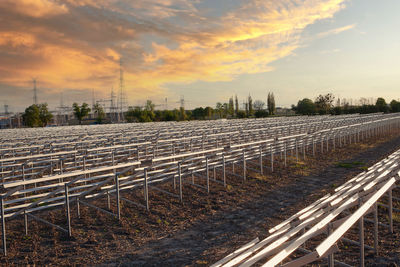 Railroad track amidst field against sky during sunset