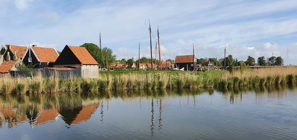 Houses by lake and buildings against sky