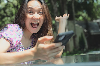 Young woman in enjoy emotion when her playing with mobile phone