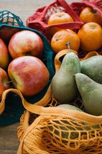 Assorted fresh fruit in cotton eco friendly sacks placed on wooden table