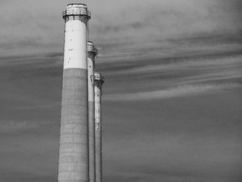 Low angle view of lighthouse by building against sky