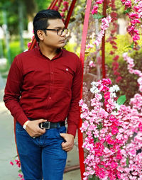 Young man standing by red flowering plants