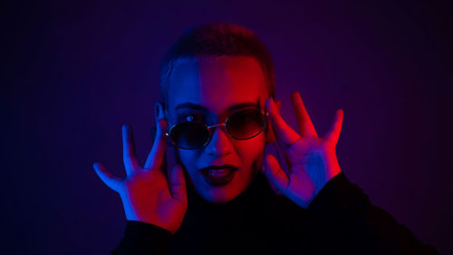 Portrait of woman wearing sunglasses against black background