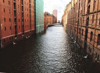 Canal in city against sky