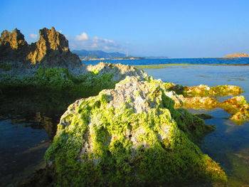 Scenic view of rocks by sea against sky