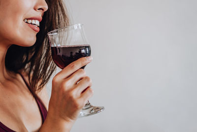 Midsection of woman holding drink against white background