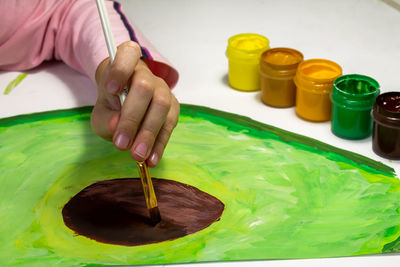Russia, anapa, 13 jan 2022. a child paints with gouache avocado fruit.