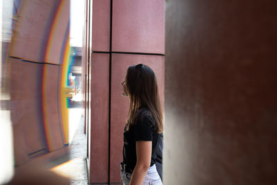 Side view of woman standing against wall