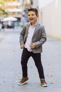 Boy laughing while standing on road in city