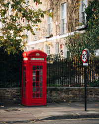 Red telephone booth on sidewalk in city