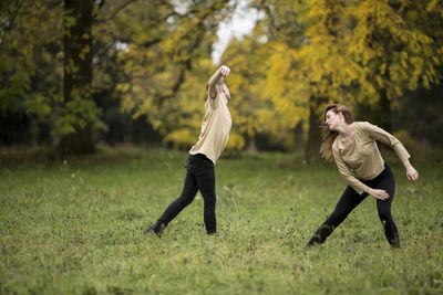 Young couple dancing on grassy field at park