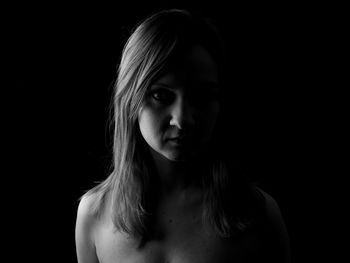 Close-up portrait of young woman against black background