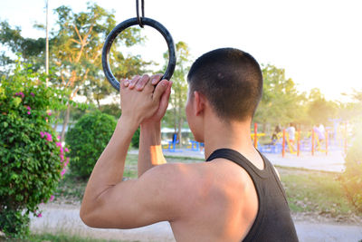 Man exercising with gymnastic rings against sky