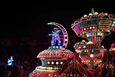 Low angle view of illuminated carousel against sky at night