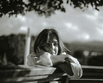 Portrait of a young woman sitting against sky