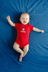 High angle view of baby girl lying on bed