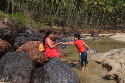 Rear view of people on rock at shore