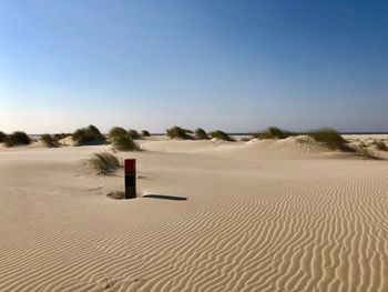 Sand dune on beach against clear blue sky