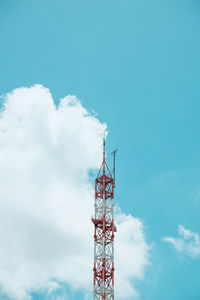 Low angle view of communications tower by building against sky