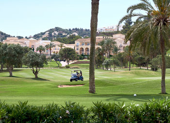 Golf cart on course against buildings