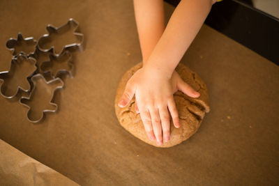 Cropped hands of girl kneading dough in kitchen