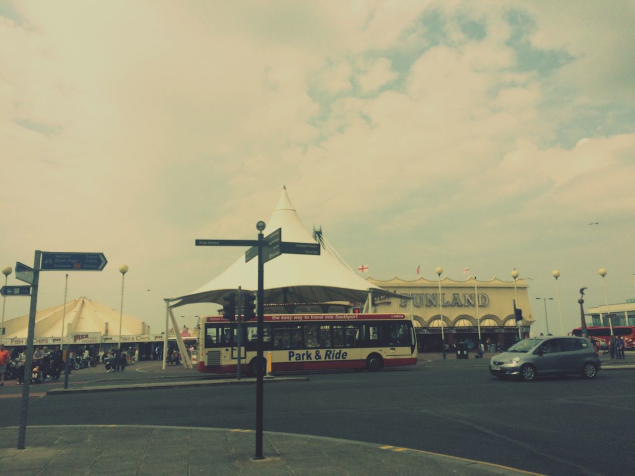 transportation, mode of transport, sky, architecture, land vehicle, car, built structure, cloud - sky, building exterior, airplane, street, travel, cloudy, road, air vehicle, incidental people, cloud, outdoors, day, on the move