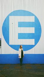 Woman standing by letter e on wall