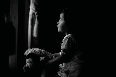 Side view of girl with toy in darkroom