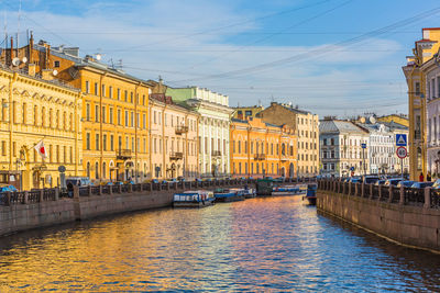 Canal amidst buildings in city against sky