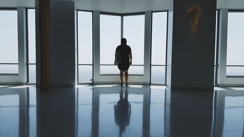 Rear view of man looking through window