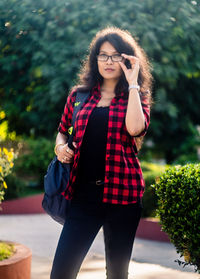 Beautiful young woman standing against tree