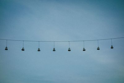 Low angle view of lighting equipment hanging against clear blue sky