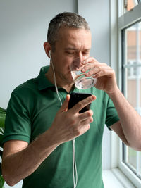 Middle aged man is talking on phone and drinking water. video call. middle aged man is talking on