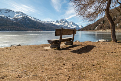 Silvaplana, switzerland, feb 21, 2023 cozy bench at the lake of silvaplana and the mount corvatsch 