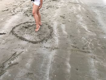 Low section of woman standing at sandy beach