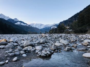 Scenic view of river by snowcapped mountains against sky