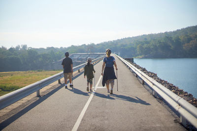 Rear view of people walking on water against sky