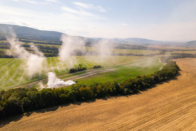 Aerial view of a tractor spreading lime on fields to improve soil quality after the harvest. 