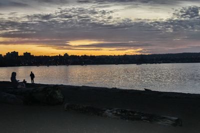 Silhouette people on beach against sky during sunset