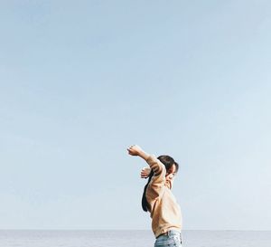 Side view of man standing in sea against clear sky