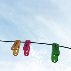 Low angle view of clothespins hanging on clothesline against sky