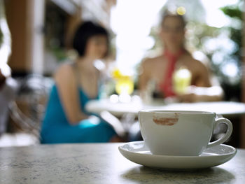 Close-up of coffee on table against defocused friends sitting at restaurant