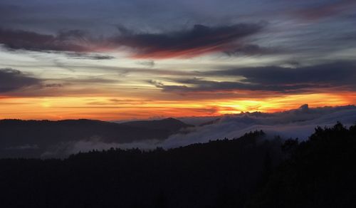 Scenic view of silhouette mountains against orange sky