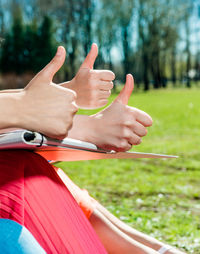 Cropped image of female friends gesturing thumbs up at park